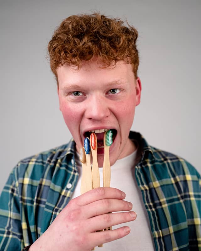 Head on portrait of a man comically pretending to put toothbrushes into his mouth