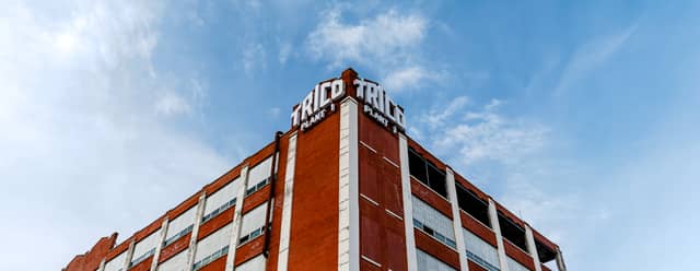 An old abandoned factory building is shown against a blue cloudy sky