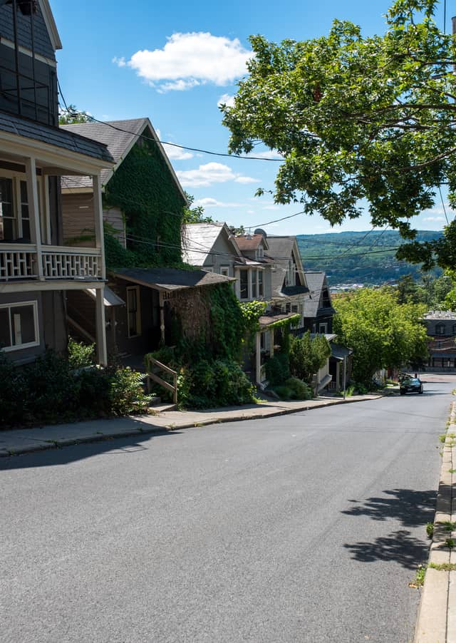 A row of single family homes are shown lining a steeply declined road