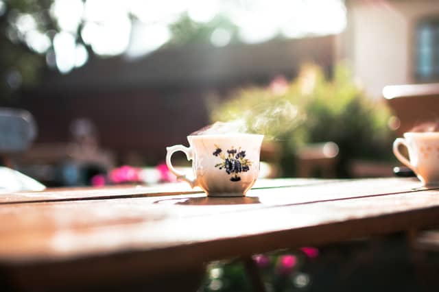 A cup of hot coffee is sitting on a table with steam rising from the top