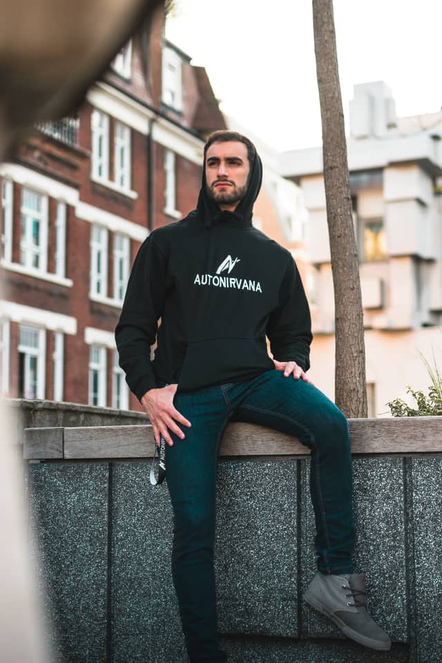 A man is sitting slightly off of a ledge, posing for a photograph