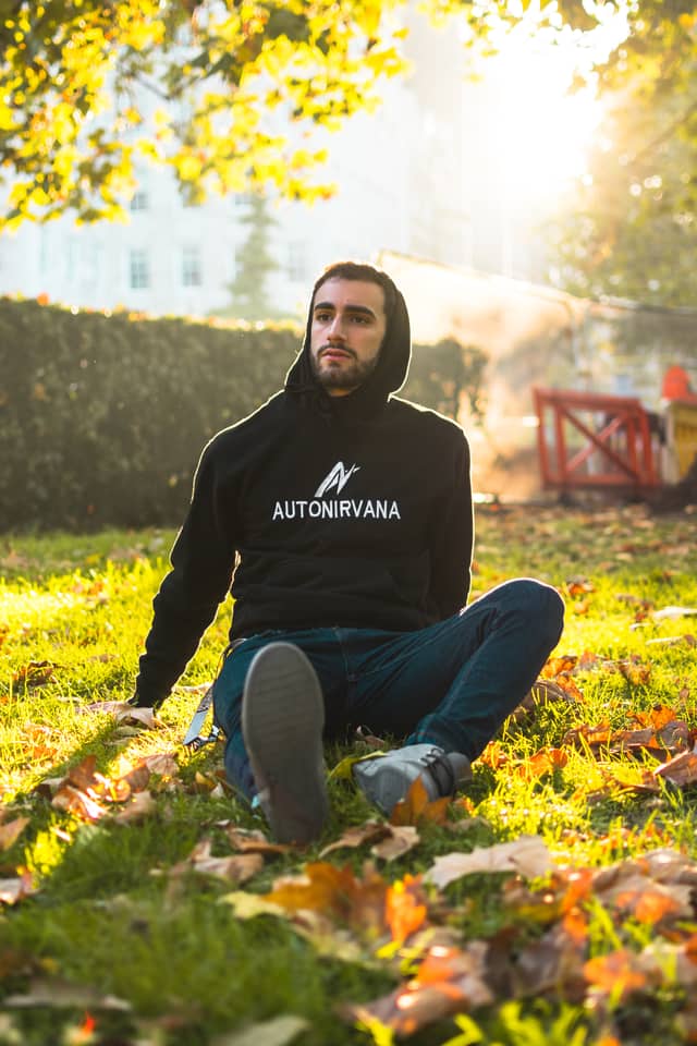 A man is sitting in the grass, posing for a photograph