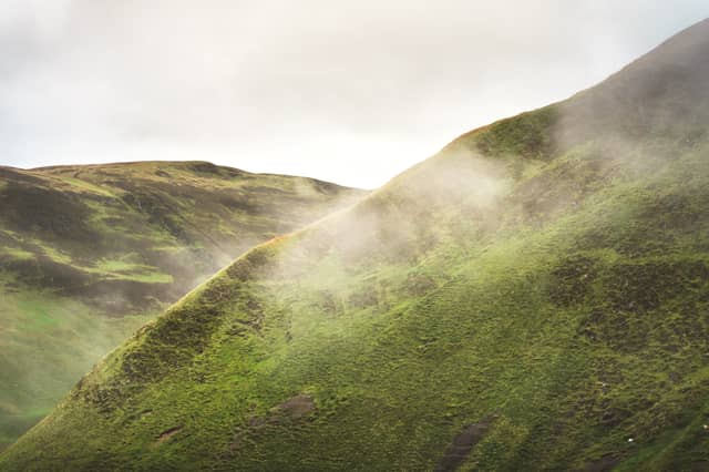 Fog rises over grass-lined hills
