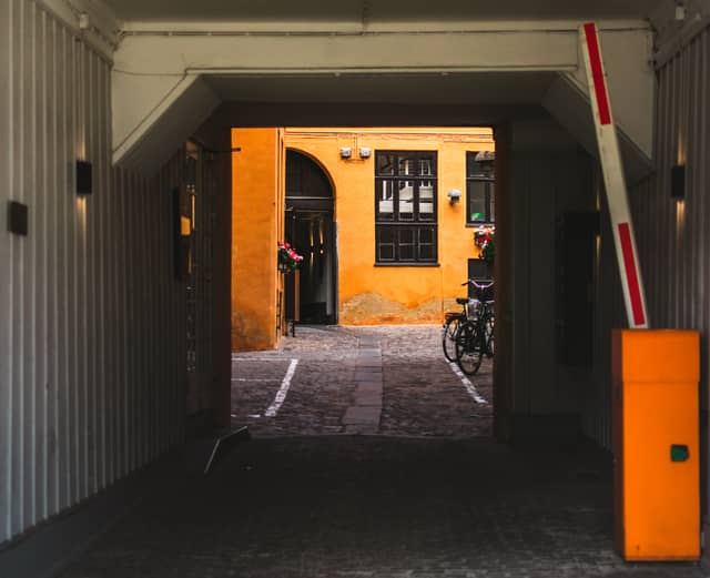 A narrow, vibrant yellow alley-way is shown through an arched entryway